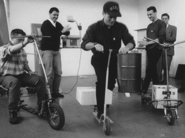 Schon damals zukunftsweisend. Projekt: Neue Mobilitätskonzepte für die Stadt, Präsentation von Funktionsmodellen für Lastenroller. Im Hintergrund links: Prof. Wolfgang Laubersheimer, im Hintergrund rechts: Student Ralf Hebecker – heute Professor für Gamedesign und -produktion an der HAW Hamburg.  Foto: © Prof. Heiner Jacob, 1992.